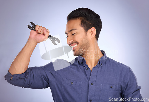 Image of Man, studio and happy with tools or spanner for handyman, maintenance or repair work. Smile of Asian model person flex strong muscle on purple background for engineer, mechanic or technician job