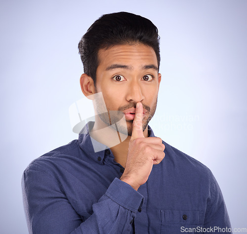 Image of Man, portrait and finger on lips for secret, gossip or silence in studio with blue background. Face of a asian model person with hand on mouth for emoji sign to surprise, hush or quiet for privacy