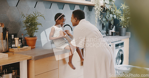 Image of Family, children and love with a girl and mother playing together in the kitchen of their home. Kids, funny and tickline with a black woman and daughter laughing while bonding in their house