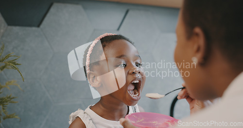 Image of Mother, child and breakfast with mom feeding girl food for nutrition, growth health and wellness in home kitchen. Black woman with girl at family house for quality time, love and eating healthy