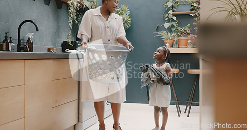 Image of Laundry, mother and child helping with folding of clothes together in a house. Happy, excited and young girl giving help to her mom while cleaning clothing from a washing machine in their home