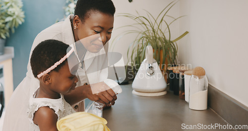 Image of Little girl helping her mother with household chores at home. Happy mom and daughter wearing gloves while spraying and scrubbing the kitchen counter together. Kid learning to be responsible by doing