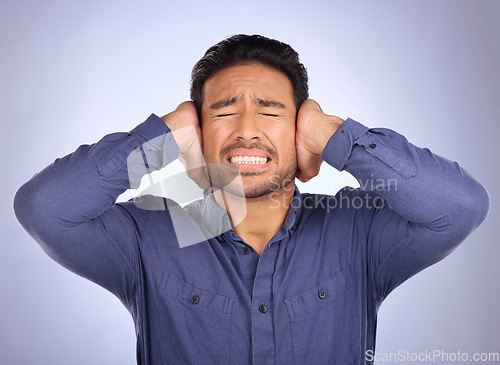 Image of Stress, noise and man closing his ears in studio isolated on a gray background. Loud, mental health and upset, angry or mad business person with headache, depression or anxiety from noisy sound.