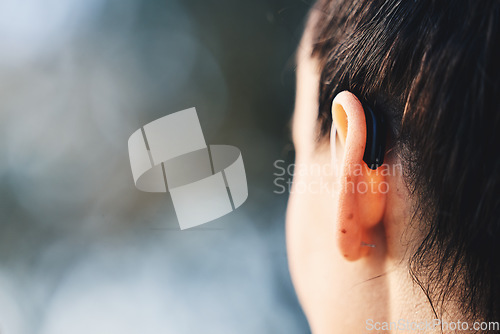 Image of Woman, ear and hearing aid implant for disability with free space for mockup or advertising. Deaf person with medical device for listening to sound or audio with technology for wellness outdoor