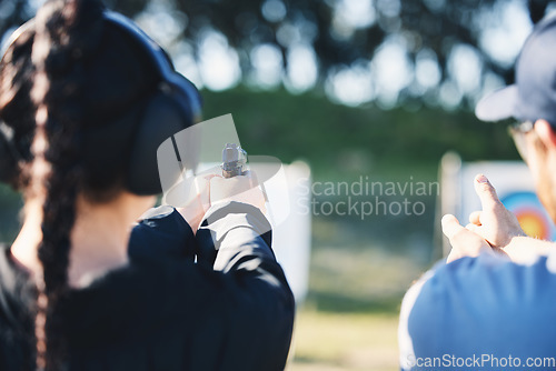 Image of Woman, gun and learning to shoot outdoor with instructor at shooting range for target training. Safety and security with hand teaching person sport game or aim with gear and firearm for focus
