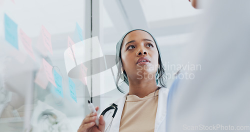 Image of Meeting, healthcare and collaboration with a doctor black woman coaching her team on glass in a hospital. Planning, training or medical with a female medicine professional talking to a clinic group