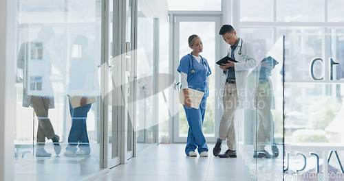 Image of Healthcare, nurse and doctor talking, walking in lobby and consultation for advice, diagnosis and tablet. Medical professionals, Asian man and woman in hospital, update charts or planning for surgery