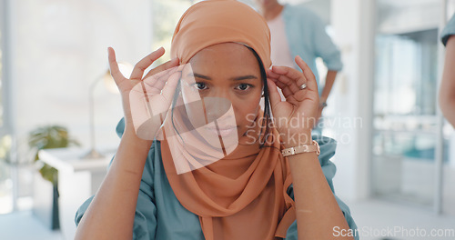 Image of Face, muslim and working with a business woman adjusting her hijab while sitting in the office for work. Hands, head or empowerment with an islamic female employee moving her headscarf in a workplace