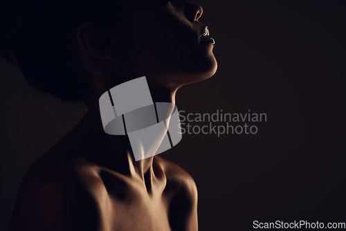 Image of Beauty, woman and silhouette dark background of skin, body and model with glow, light and art on black. Face of aesthetic model person in studio for abstract, creativity and shadow profile or space