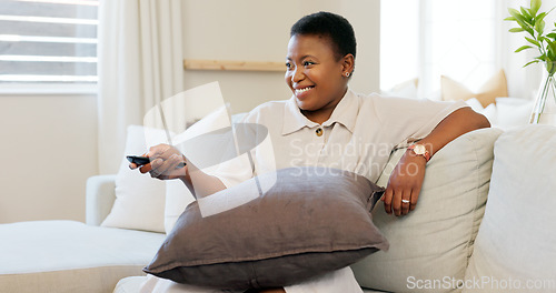 Image of Happy, smile and black woman relaxing on a sofa while watching tv in the living room of her modern house. Happiness, laughing and African lady streaming a movie while sitting on a couch in her lounge