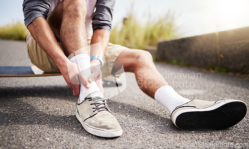Image of Fitness, athlete and man with ankle injury, pain or accident while skateboarding in the street. Sports, exercise and male skateboarder with muscle sprain, medical emergency or injured leg in the road
