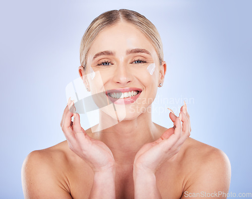 Image of Portrait, face skincare and woman with cream in studio isolated on a blue background. Dermatology cosmetics, beauty and happy female model apply lotion, creme or moisturizer product for healthy skin.