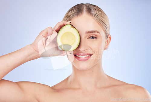 Image of Skincare, face portrait and woman with avocado in studio isolated on a blue background. Cosmetics, fruit and happy female model holding food for omega 3, nutrition or diet, healthy skin or beauty.
