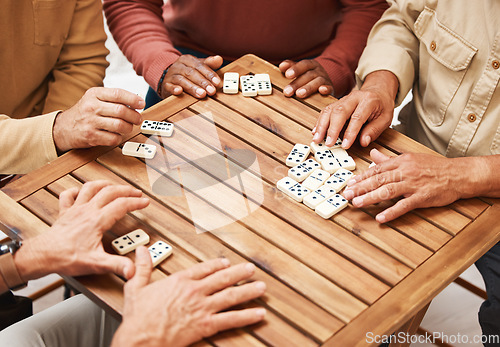 Image of Hands, dominoes and friends in board games on wooden table for fun activity, social bonding or gathering. Hand of domino players with rectangle number blocks playing in group for entertainment