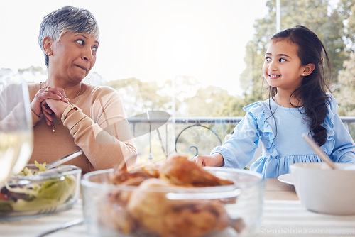 Image of Food, family and grandmother with girl a table for lunch, party or social gathering on a patio. Love, dinner and senior woman looking at grandchild while sharing a meal, happy and smile outdoors