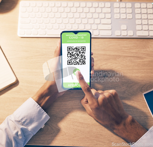 Image of Hands, phone and QR code of covid vaccination for online passport, travel or business trip at night by office desk. Hand of employee holding smartphone with approved verification for traveling