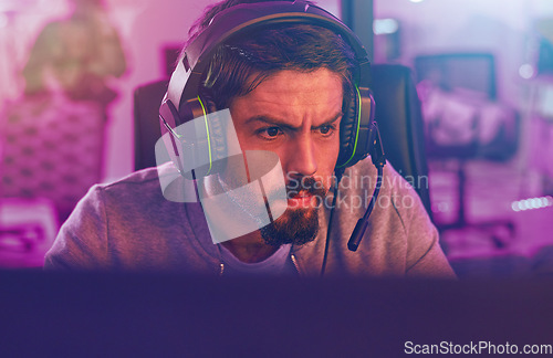 Image of Serious video game, man and esports to play online games, virtual competition and face in dark room. Gamer guy, gaming and night on headset in neon lighting, technology and digital computer streamer