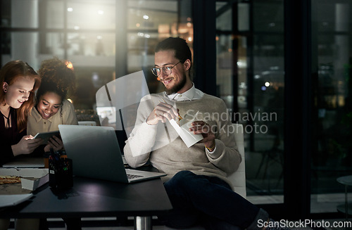 Image of Night business, man and eating noodles in office for laptop, planning or research in startup. Young employee, fast food and computer overtime in dark agency with happy team, productivity or deadlines