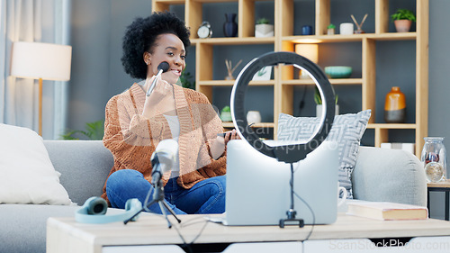 Image of A female influencer recording a makeup tutorial for her beauty blog or live streaming channel at home. Young woman creating content and engaging with her viewers and subscribers during an online vlog