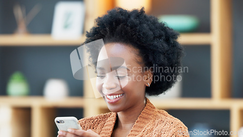 Image of Young woman smiling and laughing while texting on a phone at home. Cheerful female chatting to her friends on social media, browsing online and watching funny internet memes while relaxing in leisure