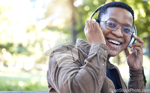 Image of Headphones, park and portrait of black man listening to music for outdoor, mental health and relaxing break in nature. Young african student or happy person with audio technology in garden or campus