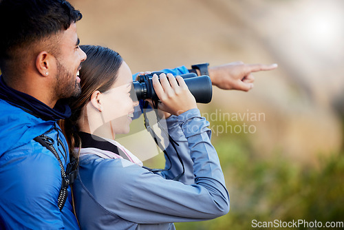 Image of Binoculars, pointing and a couple bird watching in nature while hiking in the mountains together. Forest, nature or sightseeing with a man and woman looking at the view while bonding on a hike