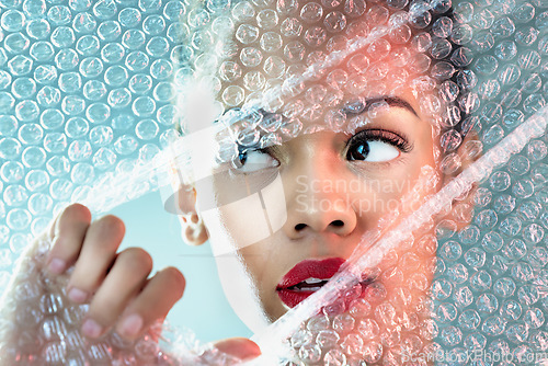 Image of Bubble wrap, beauty and face of woman with makeup, cosmetics and skincare products in studio. Creative art deco, salon aesthetic and thinking girl with glow, lipstick and luxury style with plastic