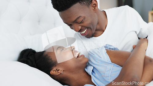 Image of Happy black couple in bedroom kiss and smile for love, romance and intimacy at house or home in morning. Young, happiness and kissing black woman and man or romantic black people dating bond together