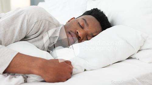 Image of Sleep, relax and dream for a black man home in bed on a weekend morning. Tired, sleeping and dreaming in bedroom alone. Relaxing, peace and comfort with head on pillow for sleepy time in bright room.