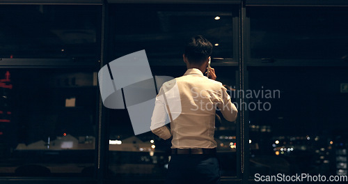 Image of Business man, phone call and window at night in modern office building for global networking or negotiation. Finance, talk strategy rear and corporate worker using phone, communication and city bokeh