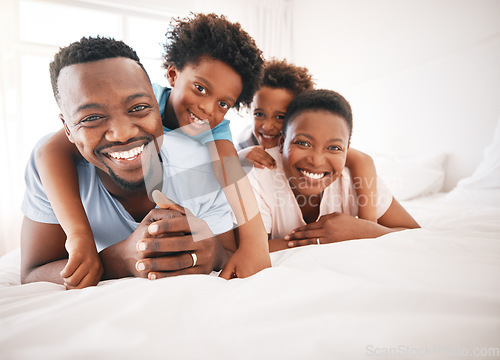 Image of Happy, bonding and portrait of a black family on a bed for playing, quality time and comfort. Smile, love and African children with parents in the bedroom for happiness, relaxation and stress relief