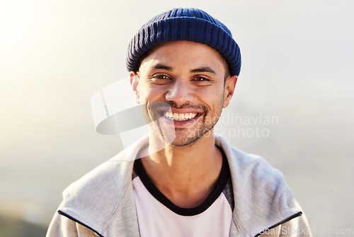 Image of Portrait, happy and nature with a man in a beanie, standing outdoor in the wilderness on a gray sky. Face, smile and lifestyle with a handsome young male outside for travel, freedom or adventure