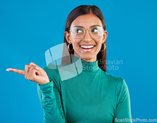 Image of Mockup, Indian woman and pointing with space, smile and advertising with girl against a blue studio background. Female, lady and gesture for direction, happiness and branding development with smile