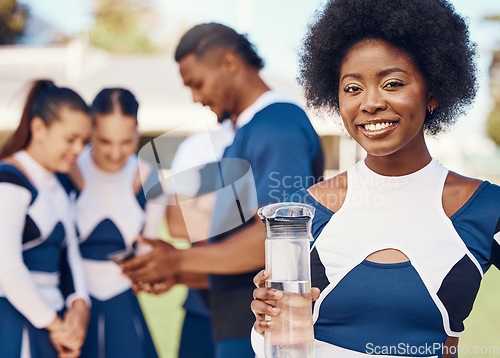 Image of Cheerleader, portrait or black woman drinking water in cheerleading in training or exercise workout. Happy smile, fitness or face of healthy girl athlete with liquid for hydration on field in game