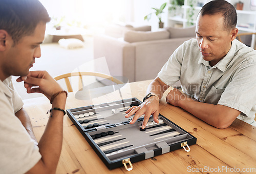 Image of Man, senior and play backgammon in house with focus, strategy and contest for thinking, moving or son by table. Elderly man, board game competition and relax with bonding, love and family home lounge