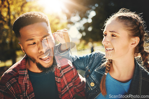 Image of Playful, park and a girl pulling the ear of her boyfriend outdoor during summer for love while on a date. Couple, game or nature with a young man and woman outside, bonding in a garden for romance