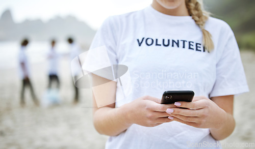 Image of Hands, phone and volunteer woman at beach for cleaning, social media and web browsing. Earth day, environmental sustainability and female with 5g mobile smartphone at seashore for community service.