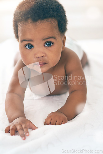 Image of Cute baby, black kids and portrait of crawling on bed for play, fun and relax in nursery room. Young african infant child, girl and face of healthy development, growth and learning to crawl in house