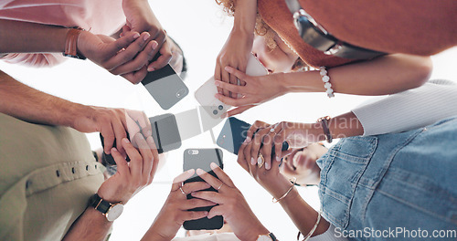 Image of Hands, phone and communication with friends standing in a huddle or circle from below for networking. Social media, mobile and 5g with a man and woman friend group connected to the internet together