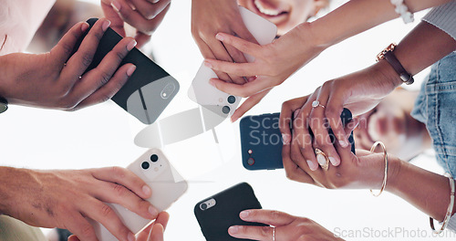 Image of Hands, phone and communication with friends standing in a huddle or circle from below for networking. Social media, mobile and 5g with a man and woman friend group connected to the internet together