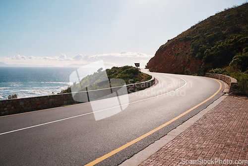 Image of Mountain, road and ocean view with no people for travel, destination or sightseeing in Cape Town. Nature, beauty on empty street for road trip, vacation or holiday on South Africa blue sky background