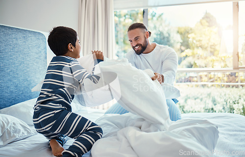 Image of Love, father and son in bedroom, pillow fight and happiness on vacation, quality time and break. Family, dad and boy on bed, playful and smile for bonding, loving and carefree with joy and cheerful