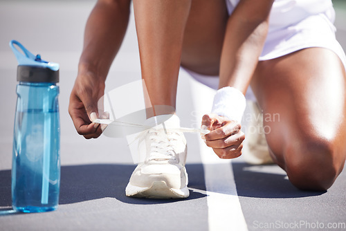 Image of Woman, hands and tying shoe lace on tennis court getting ready for sports match, exercise or workout outdoors. Hand of sporty female tie shoes in preparation for sport training, game or activity