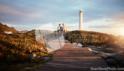 Image of Lighthouse, family walking and nature adventure on a summer holiday at sunset by the sea. Ocean, beach walk and outdoor with a mom, father and child together with love and parents support at dusk