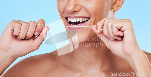 Image of Happy man, dental floss and cleaning teeth in oral hygiene or grooming against a blue studio background. Closeup of male person with big smile in flossing, tooth whitening or gum and mouth care