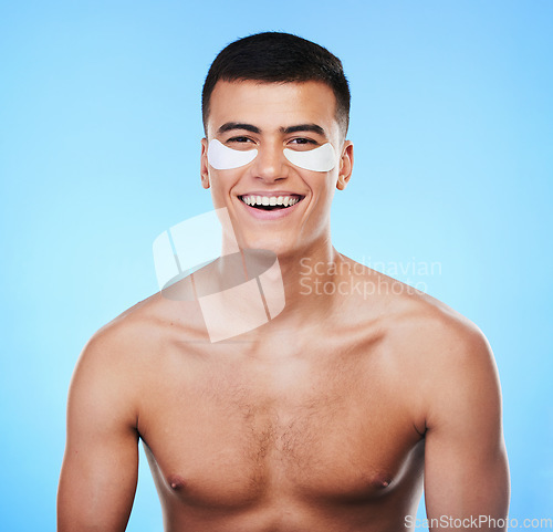 Image of Happy man, beauty and smile with eye patch for skincare, grooming and clean with hygiene on blue background. Skin treatment, cosmetics product and wellness, portrait and dermatology in a studio