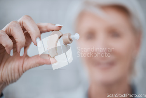 Image of Hand, closeup and hearing aid with senior woman for audio, sound or listen with healthcare in retirement. Elderly lady, deaf or person with disability holding technology for ear implant for wellness