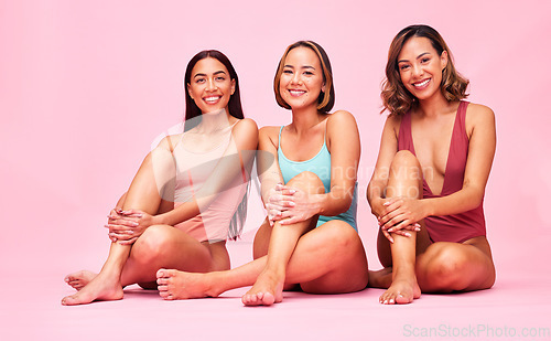 Image of Beauty, bikini and group of women in studio, sitting together with smile and body positivity portrait. Diversity, summer fashion and happy swimwear models with self love, equality and pink background