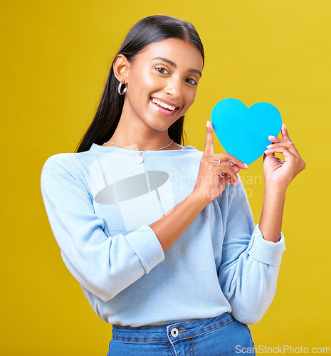 Image of Portrait, donation and woman with blue heart in studio for help, hope or empathy on yellow background. Face, charity and social media, poster or thank you, support or autism or people with disability