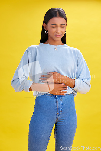 Image of Sick, stomach pain and woman with constipation, digestion problem or diarrhea in studio isolated on a yellow background. Abdomen gas, disease and person with menstrual cramps, endometriosis or hernia